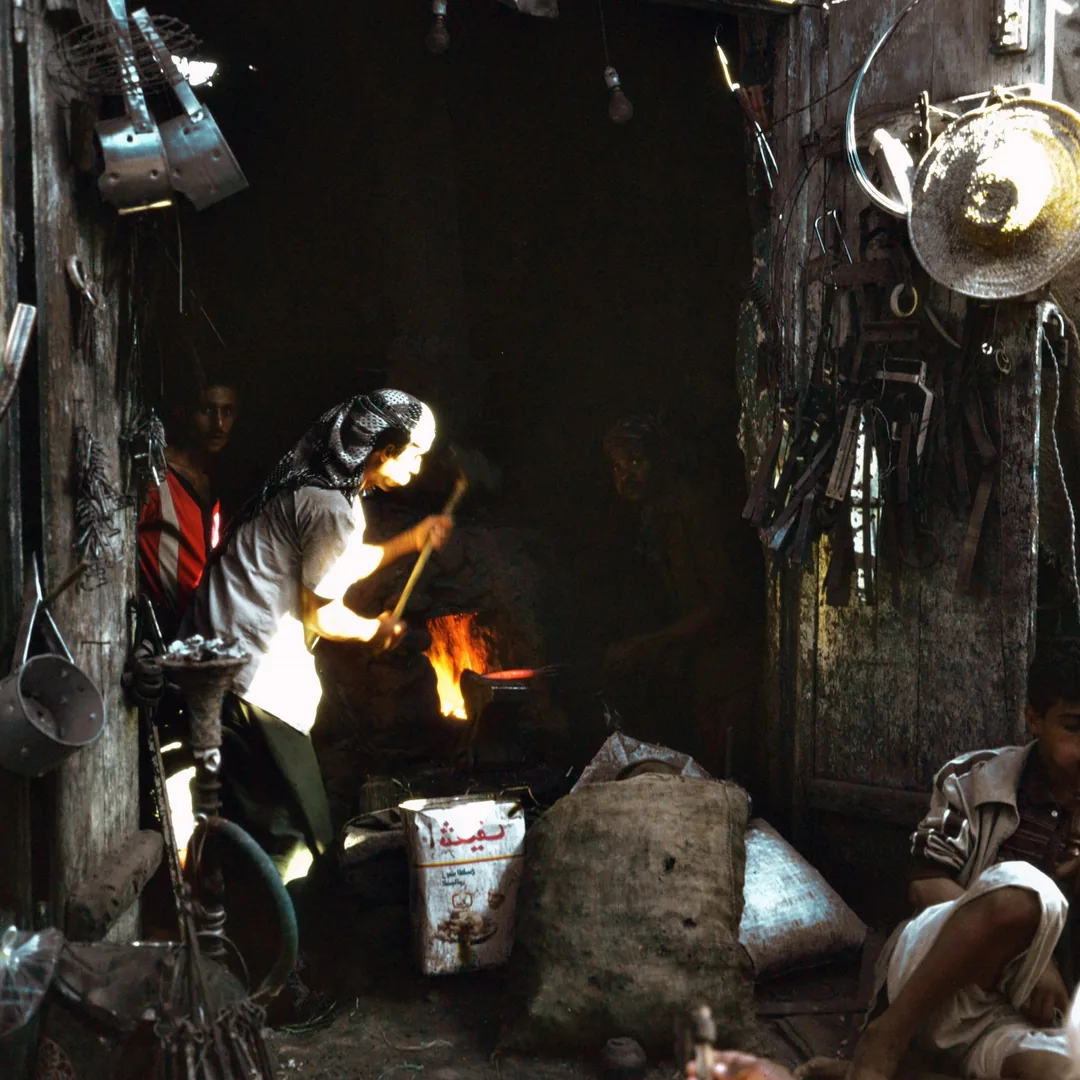 Interior de una fragua con el hogar encendido, el yunque y las herramientas de forja colgadas cerca